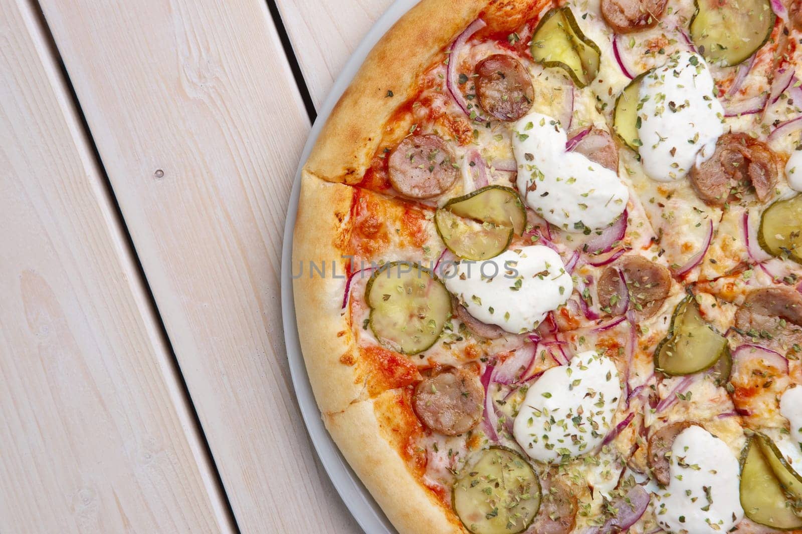 Top view of pizza with sausage, pickled cucumber and mushrooms