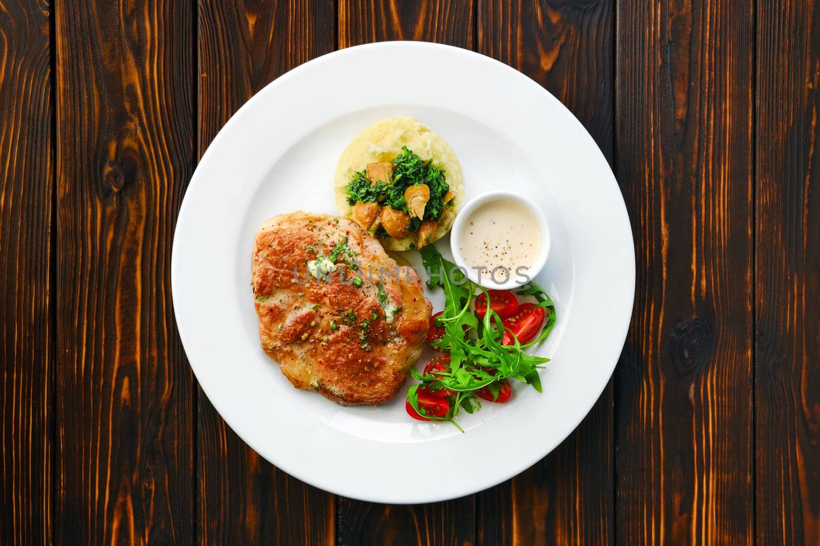 Top view of fried chop pork cutlet with mashed potato and boletus edulis gravy served with fresh tomato cherry and arugula