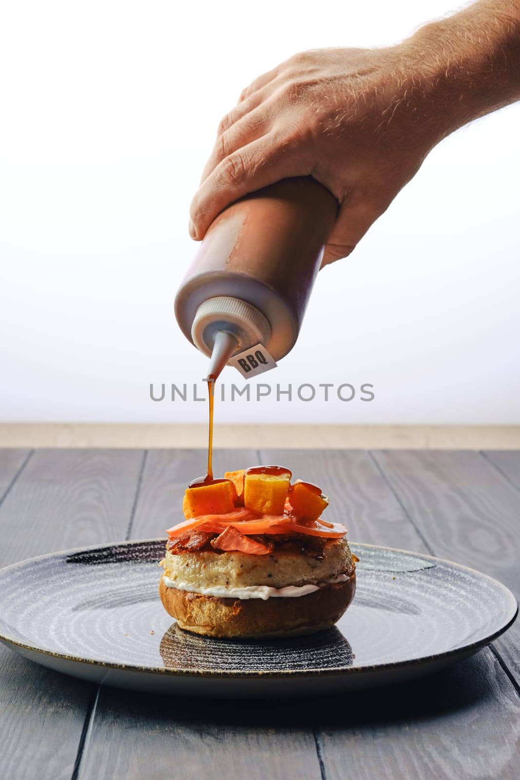 Making burger with beef, bacon, pumpkin and tomato - pouring barbecue sauce