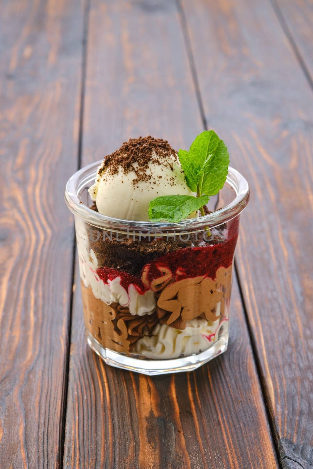 Dessert with cookie crumbs, soft cheese, strawberry jam and ice cream with grated chocolate