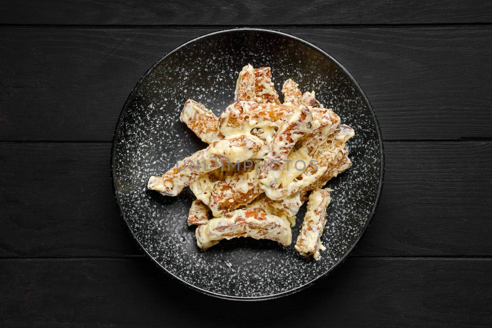 Overhead view of salty bread sticks covered with melted cheese on a plate