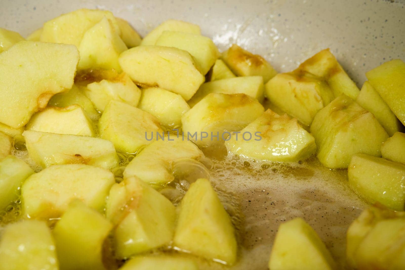 Slices of green apples caramelizing in frying pan with sugar (photo with shallow depth of field)