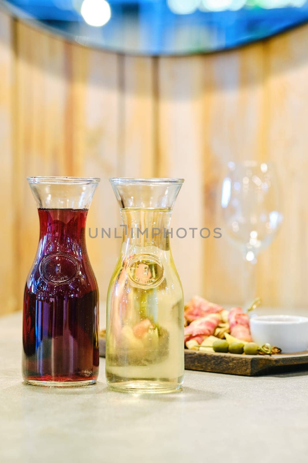 Two decanters with wine and plate with snack on background (soft focus photo with shallow depth of field)