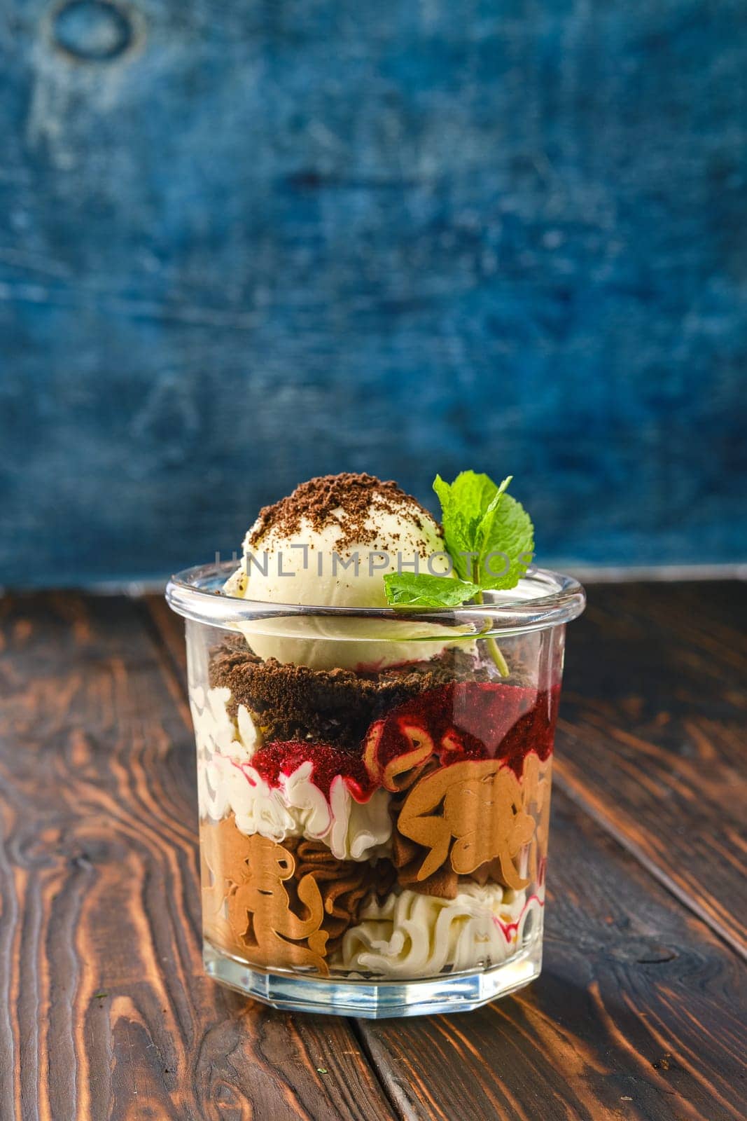 Dessert with cookie crumbs, soft cheese, strawberry jam and ice cream with grated chocolate