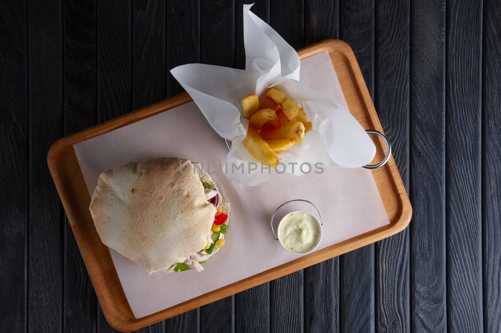 Top view of pita bread with chicken and vegetables served with fried potato