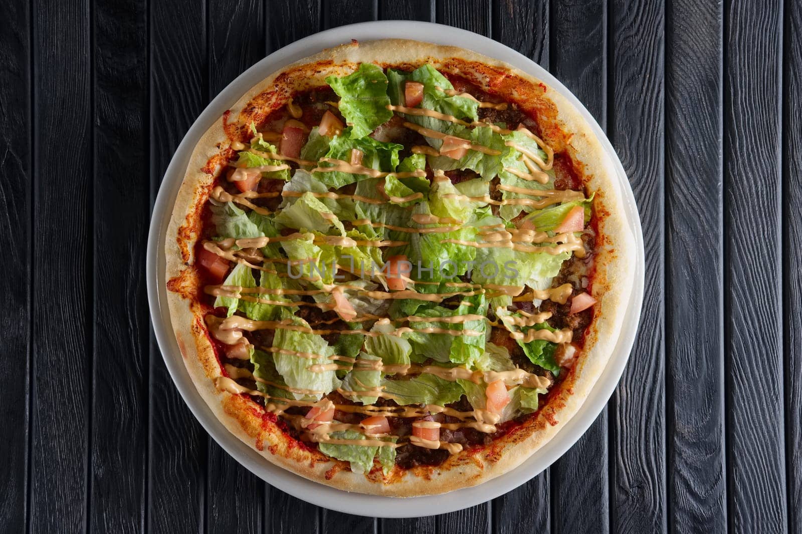 Pizza with ham, mustard sauce and salad leaves