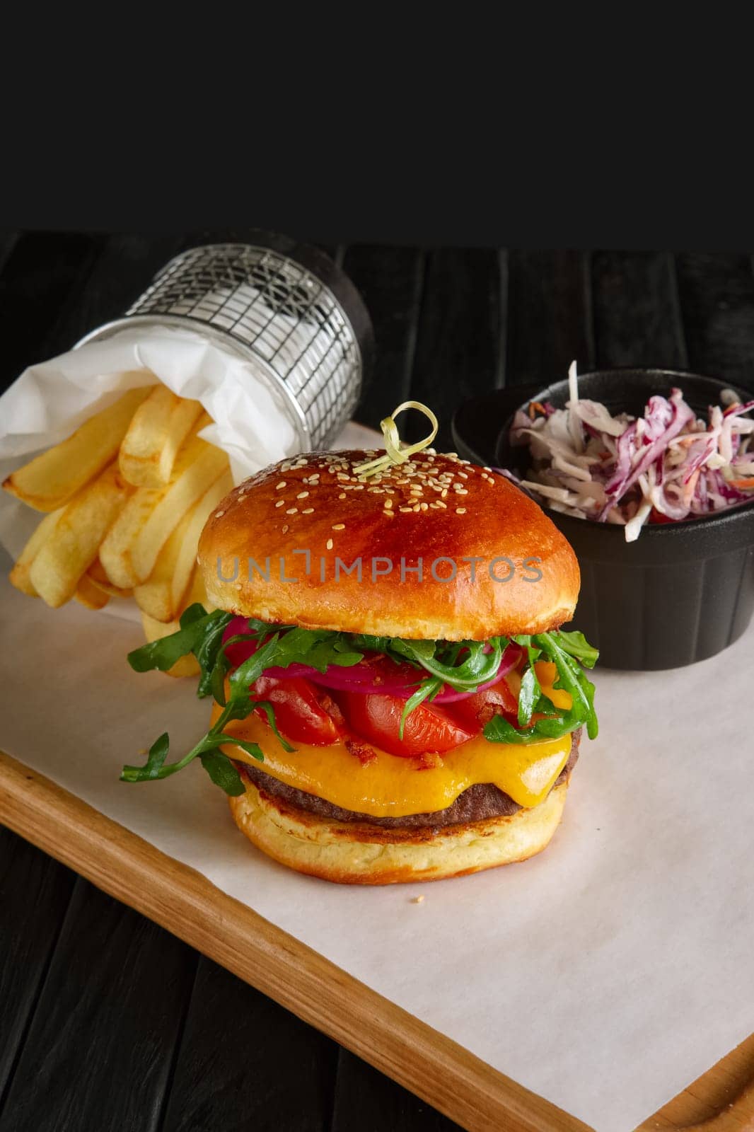 Juicy beef burger with lingonberry sauce, melted cheese, arugula served with fried potato and red cabbage