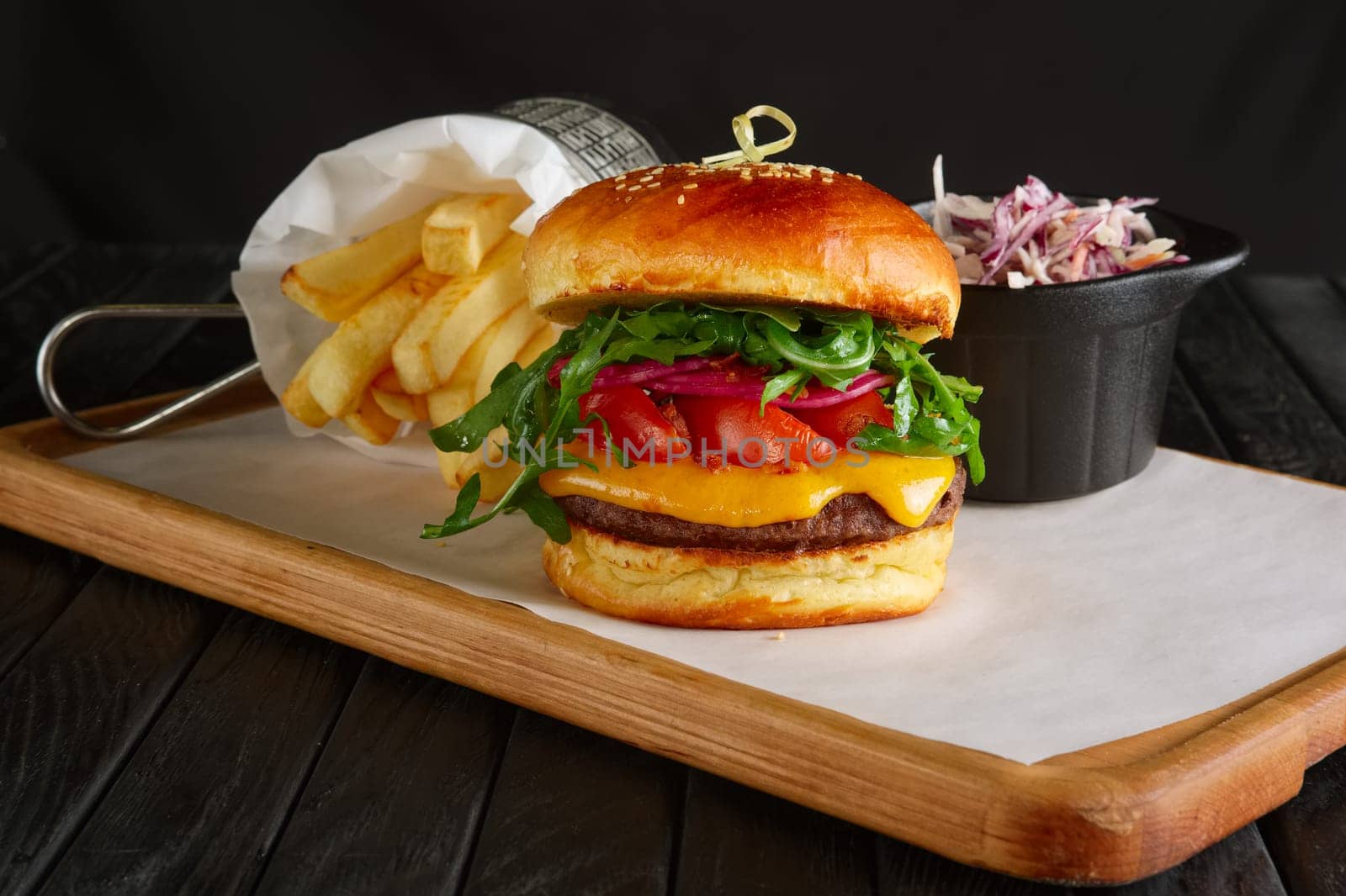Juicy beef burger with lingonberry sauce, melted cheese, arugula served with fried potato and red cabbage
