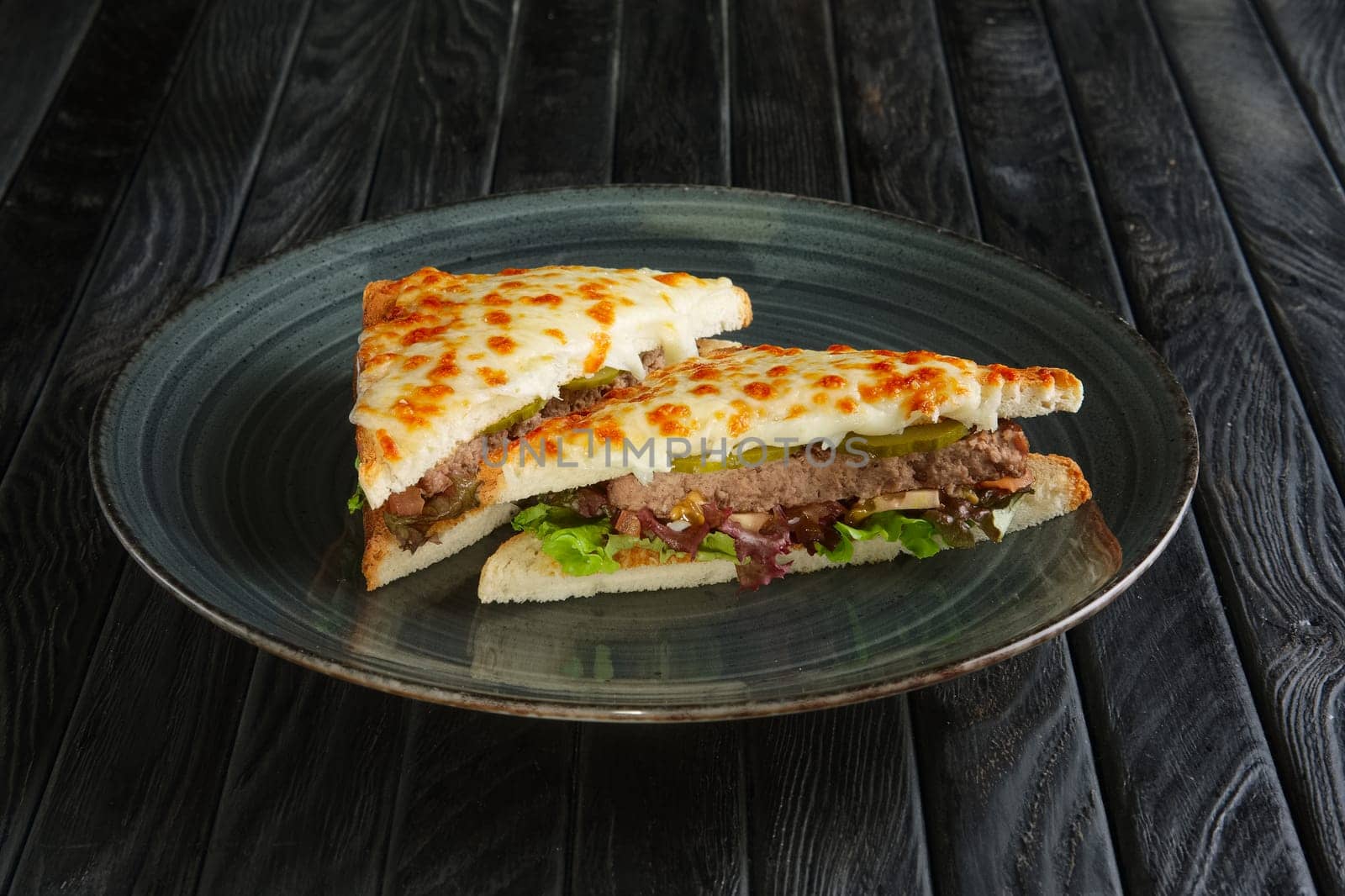 Club sandwich with meat, pickled cucumber , salad and melted cheese