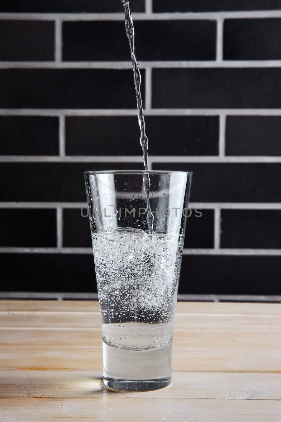 Pouring mineral water in highball glass. Lifestyle cafe shot.
