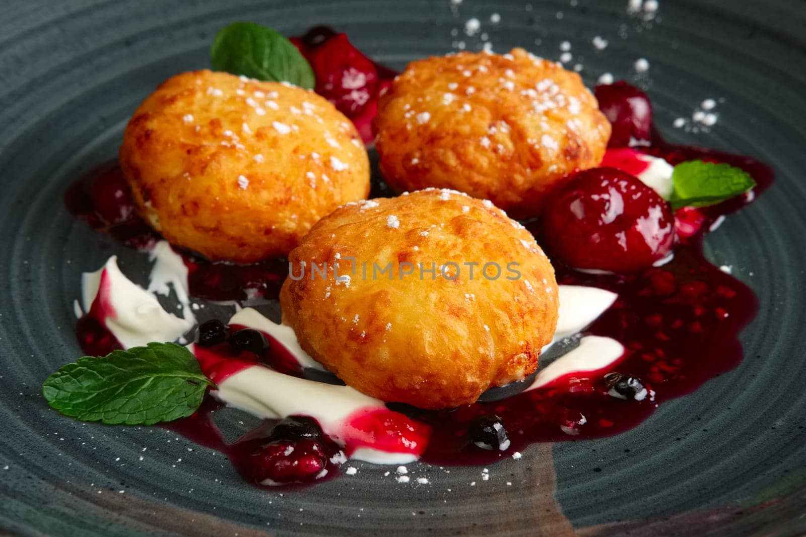 syrniki, curd pancake with cherry and raspberries jam decorated with mint leaves