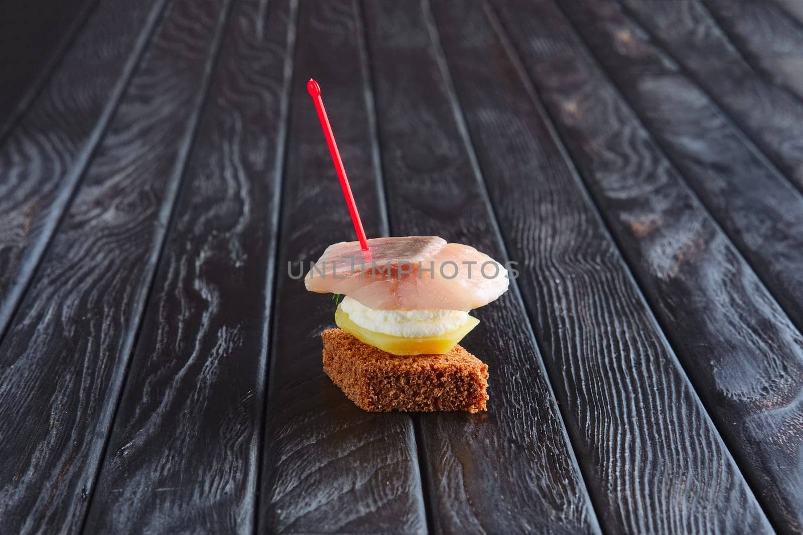 Appetizer for reception. Small sandwich with potato and herrings on skewer