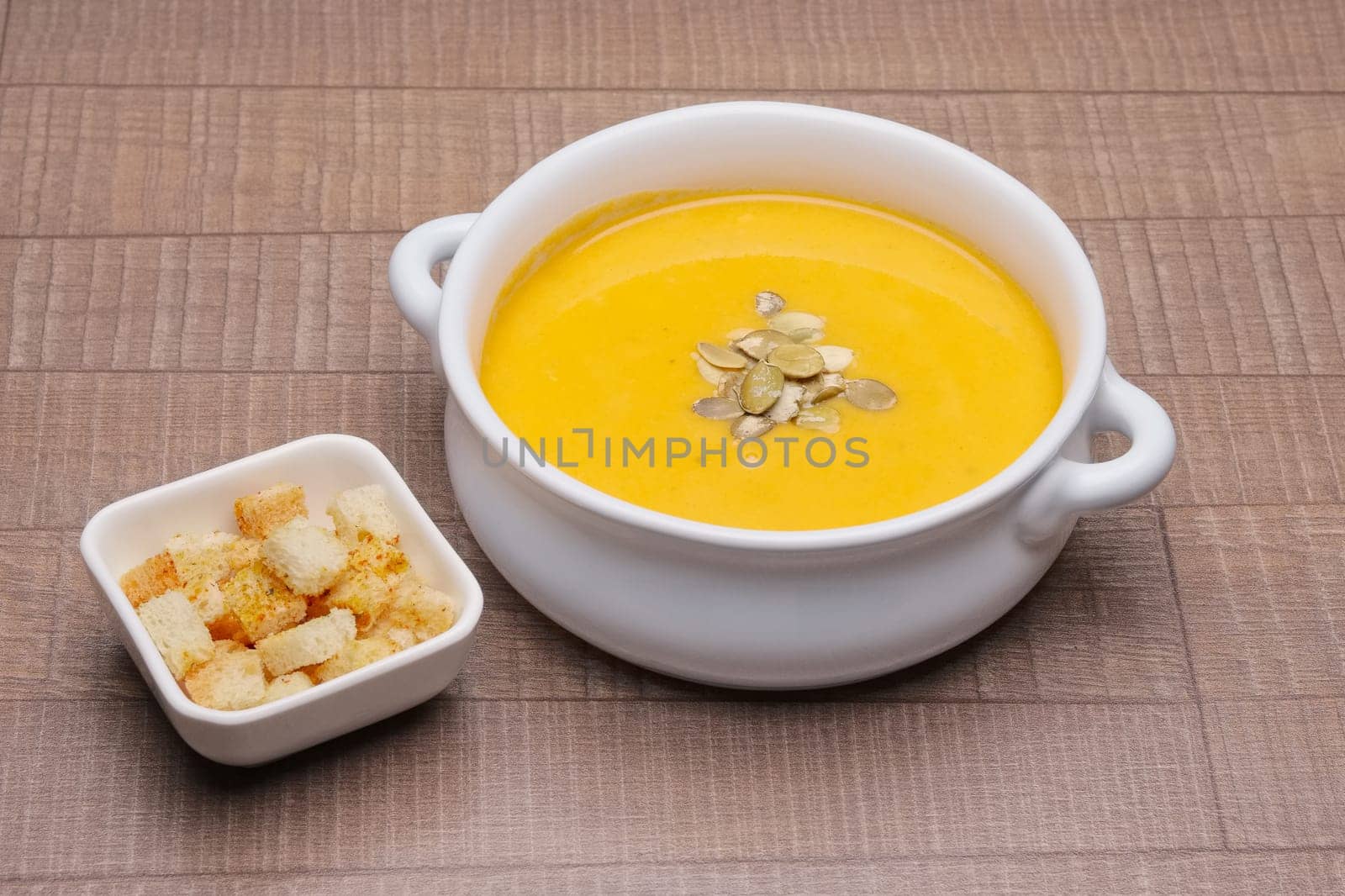 Plate with pumpkin soup with seeds and crackers