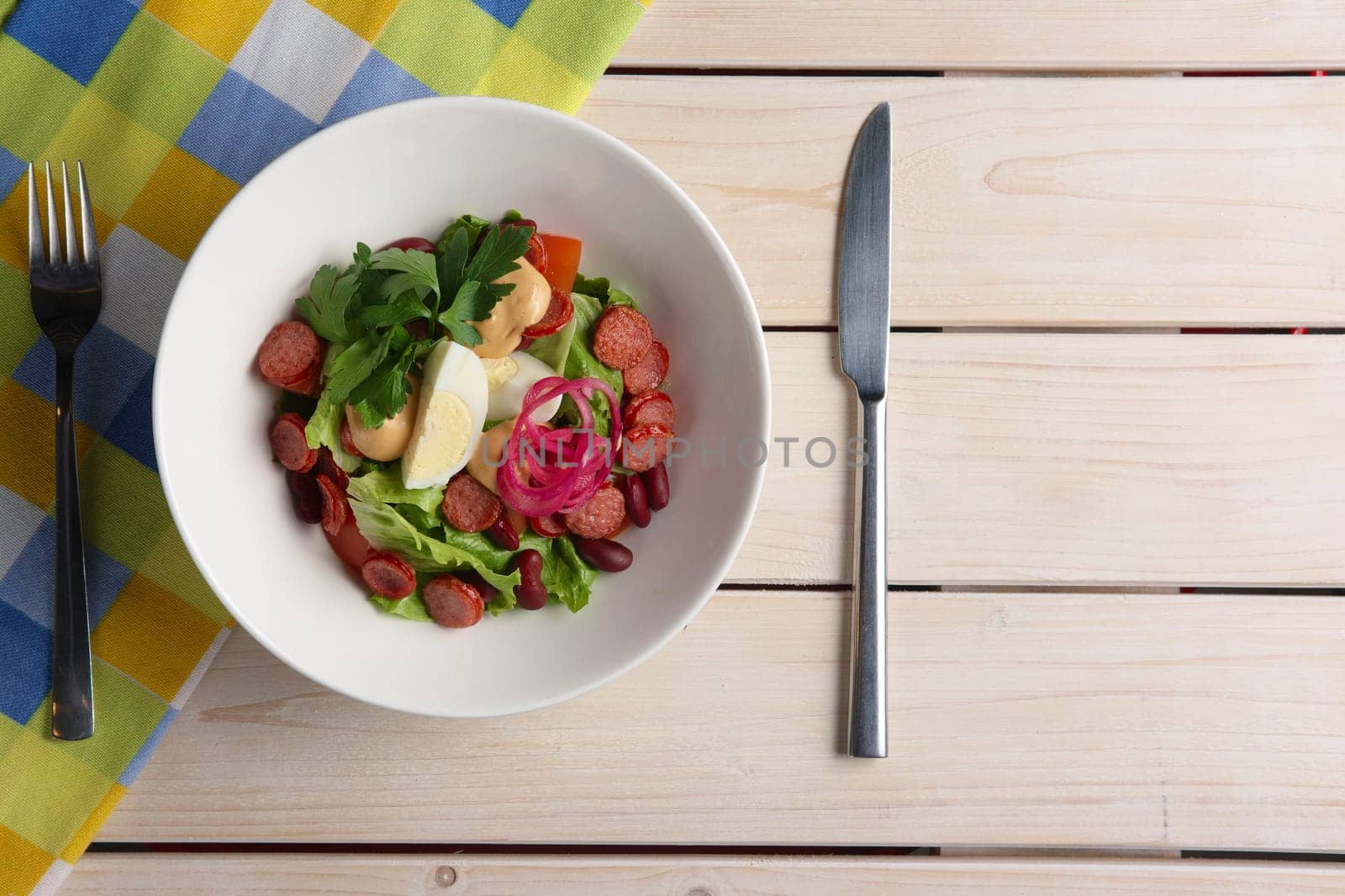 Salad with smoked sausage and egg. Top view of served table