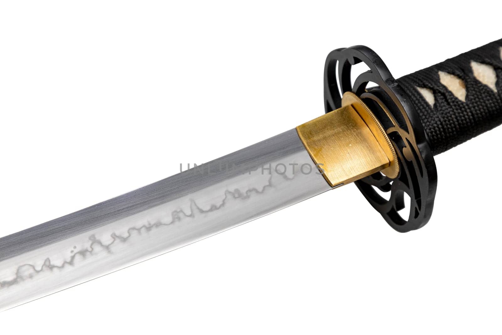 The 'habaki' - collar is made of polished brass. It is at the base of a Japanese sword blade with a wavy pattern on the sharp part. isolated on a white background. Selective focus.