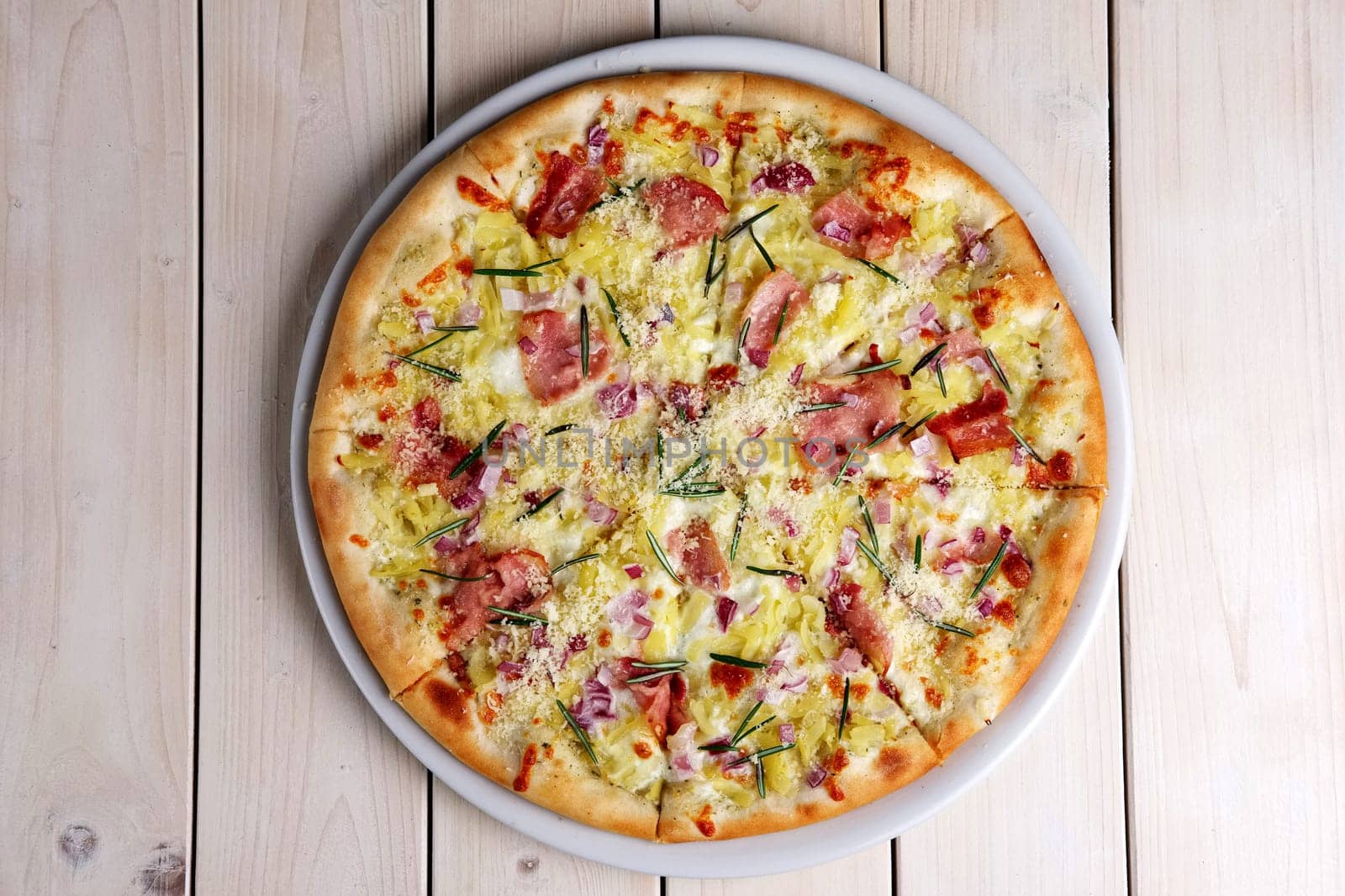 Top view of pizza with bacon chips, ham, cheese and rosemary