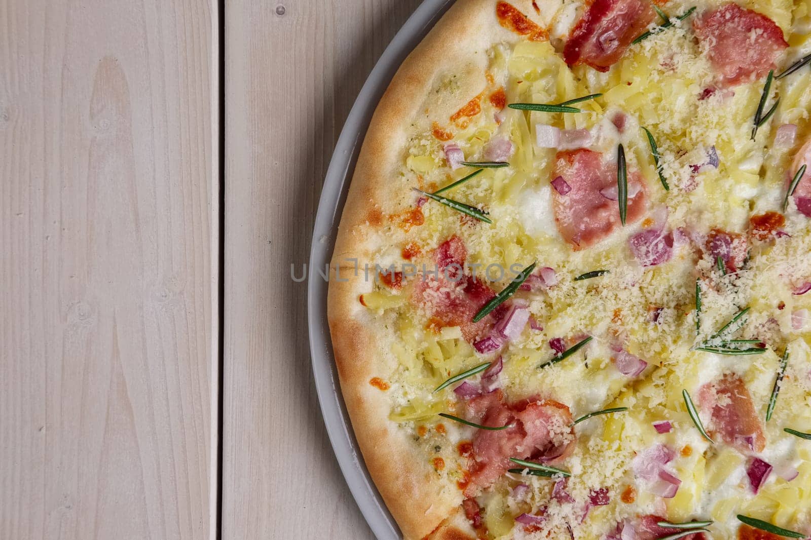 Top view of part of pizza with bacon chips, ham, cheese and rosemary. Copy-space for text