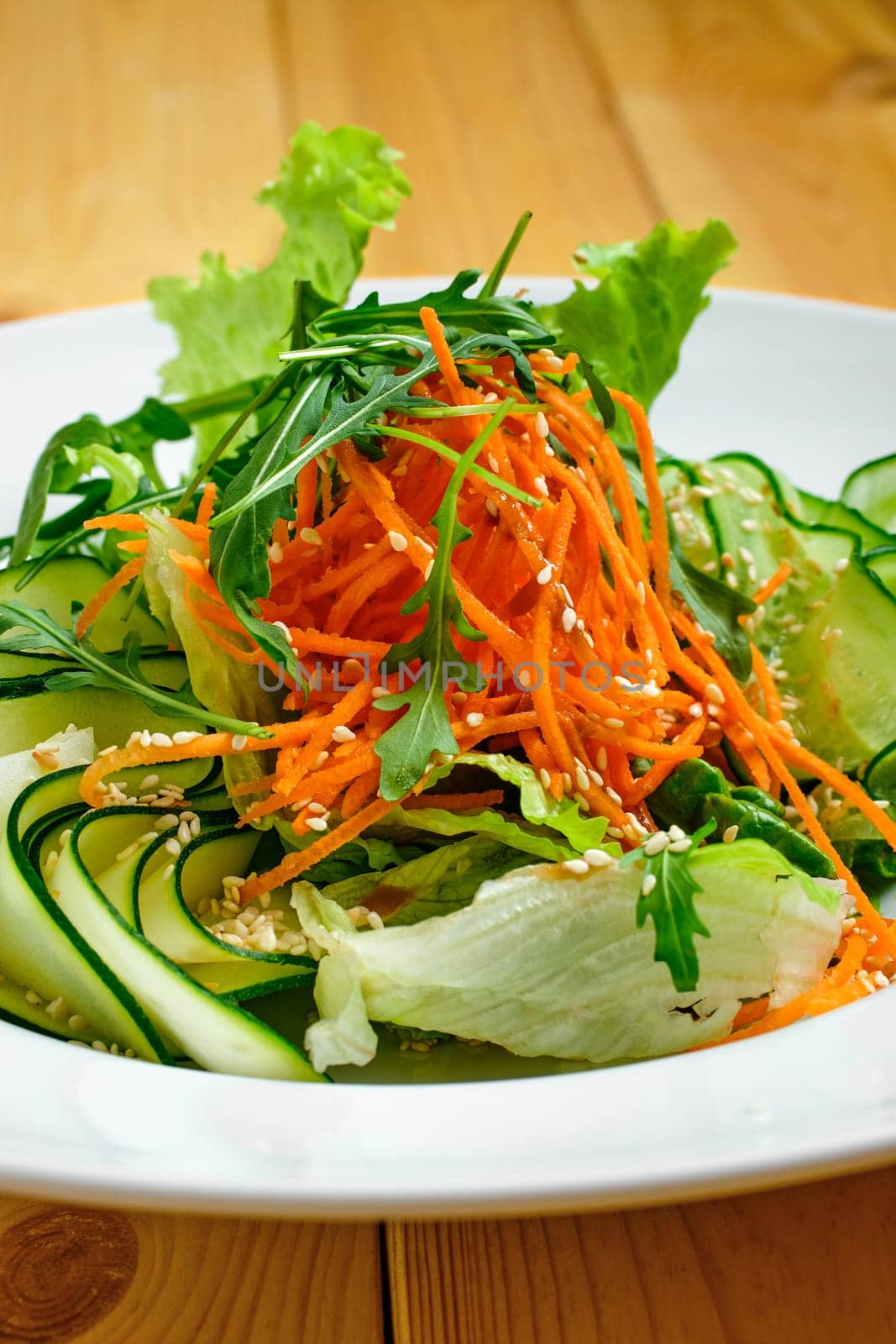 Macro photo of salad with cucumber, spicy carrot, arugula and sesame