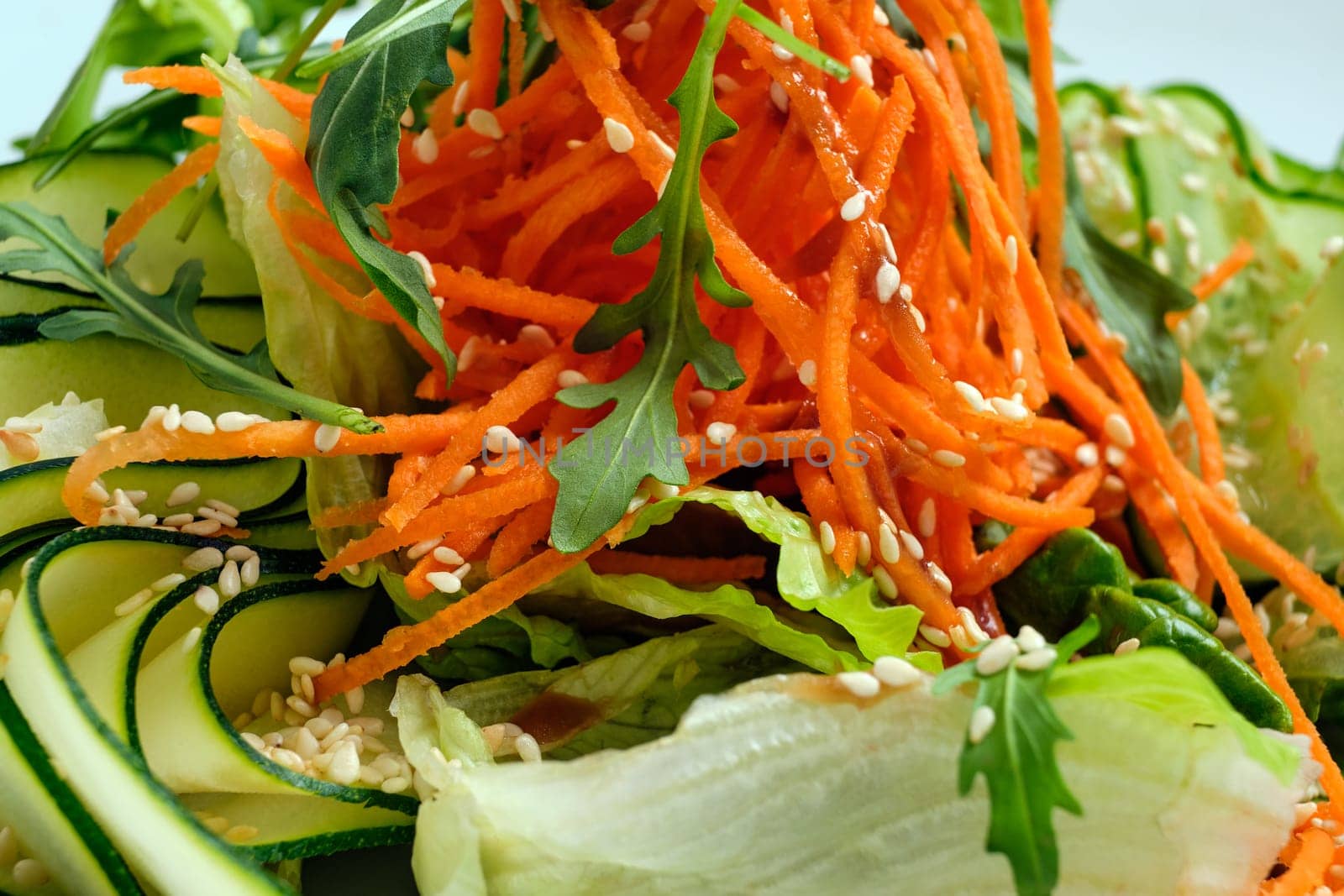 Macro photo of salad with cucumber, spicy carrot, arugula and sesame