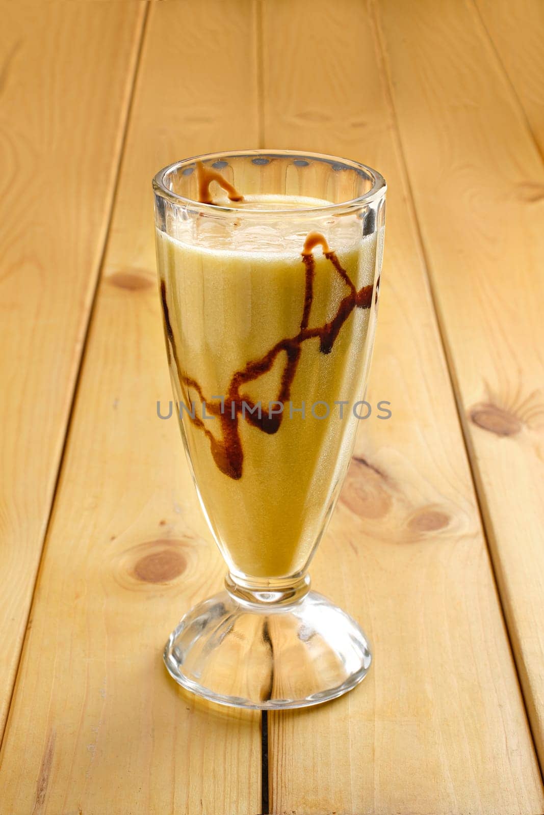 Glass of banana smoothie on wooden table