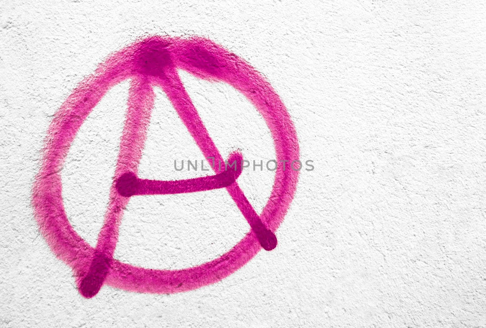 Pink anarchy symbol on wall. Ideal for textures, backgrounds and concepts. Copy space.