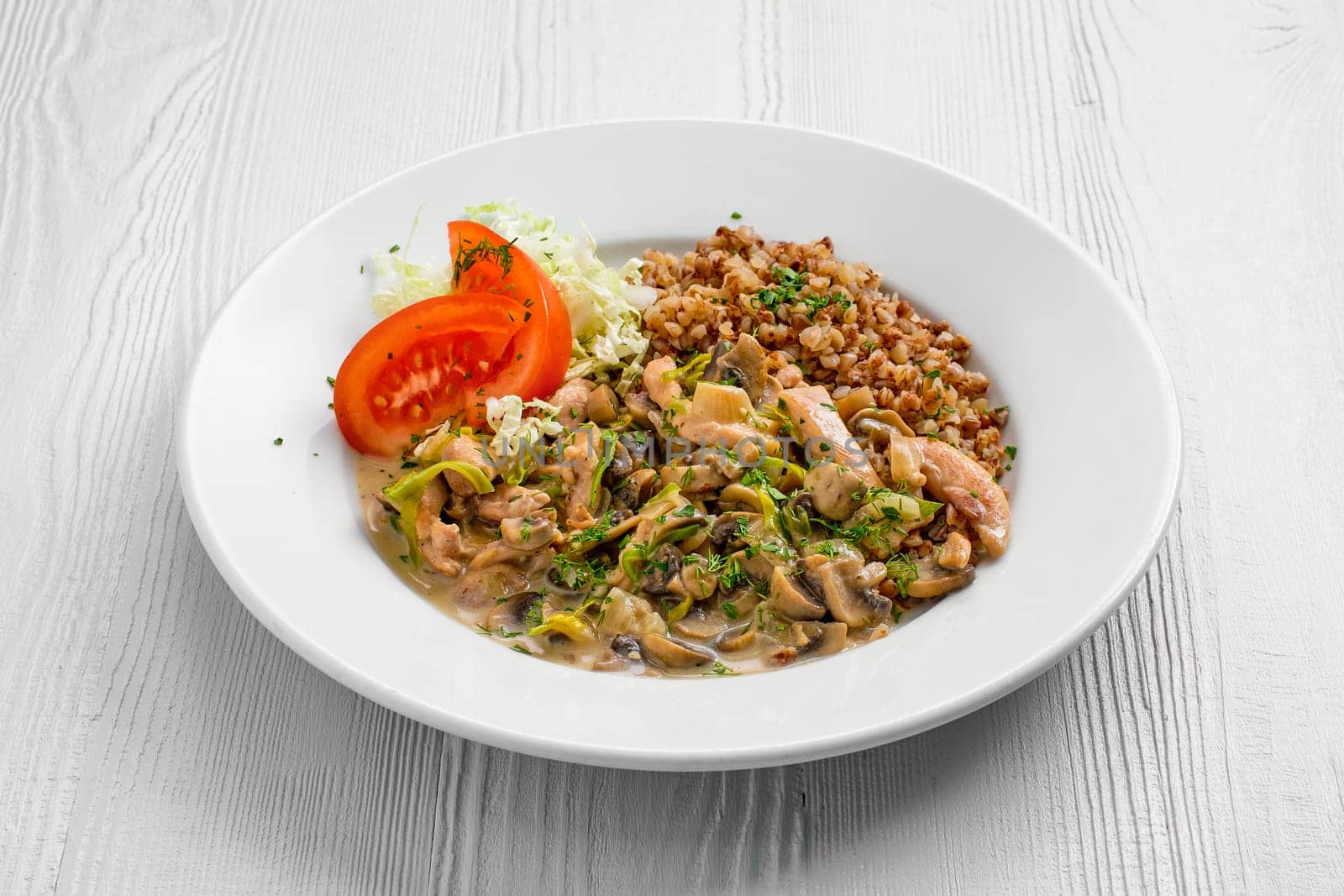 Plate with chicken goulash, mushroom, buckwheat and tomato cabbage salad