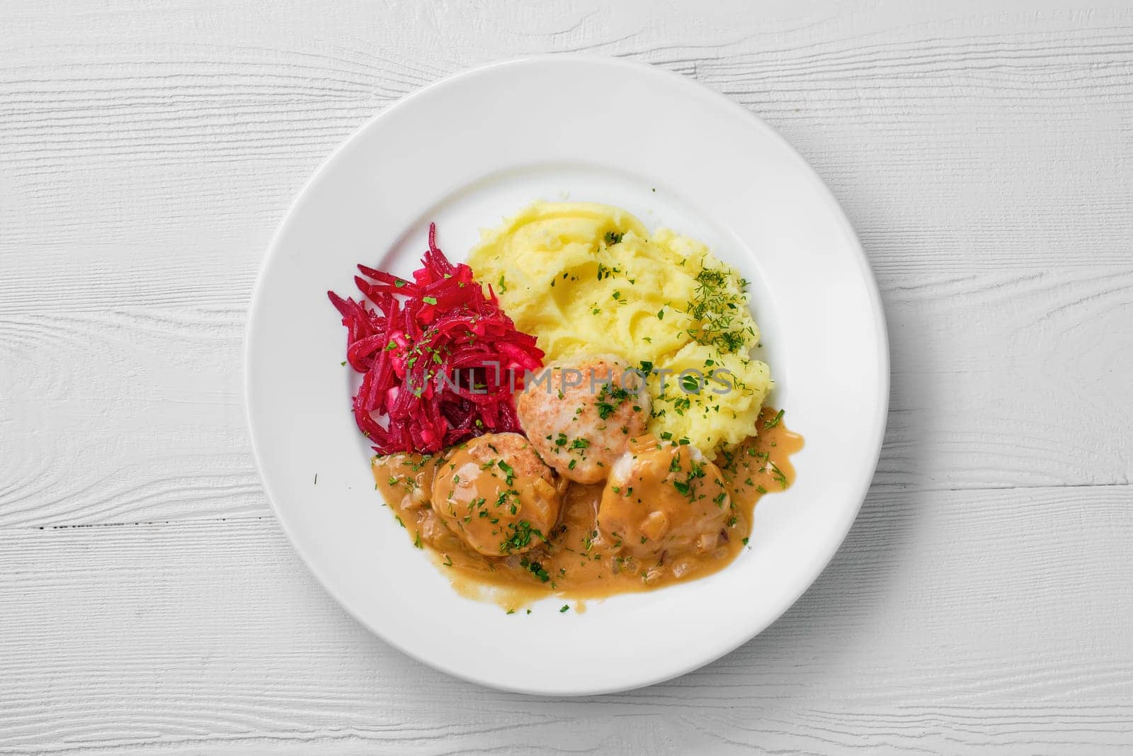Top view of plate with meatballs, mashed potato and beetroot salad