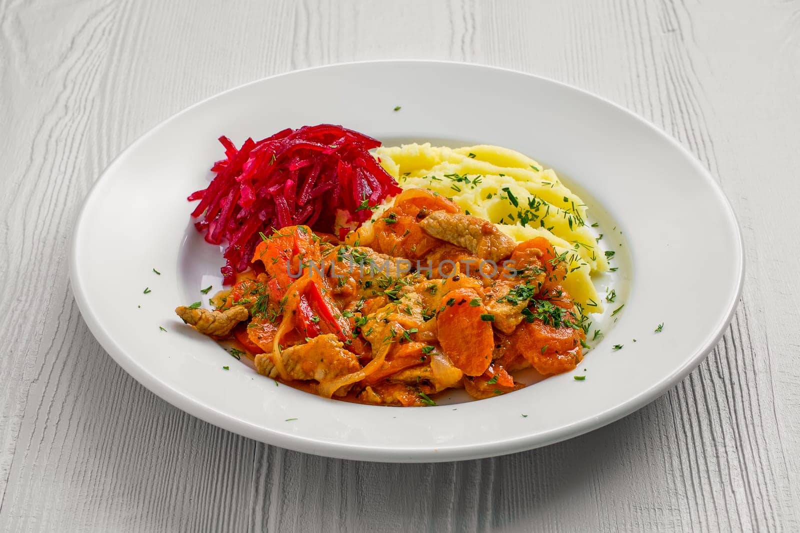 Plate with beef goulash, mashed potato and beetroot salad