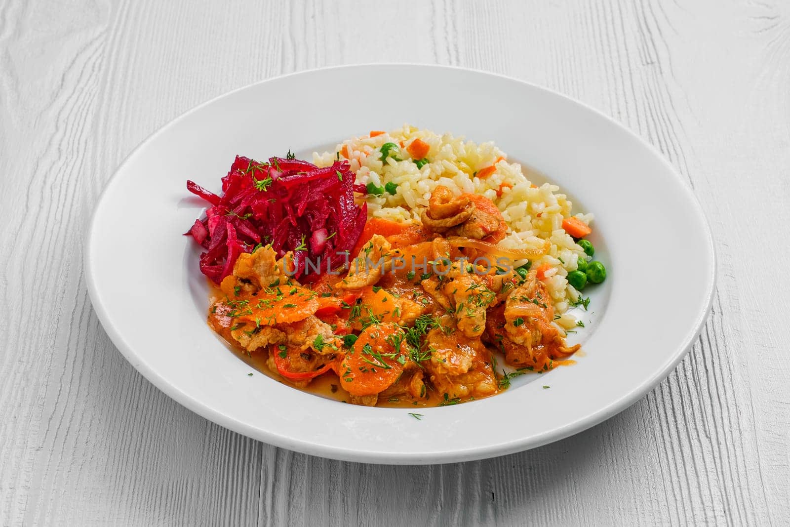 Plate with beef goulash, rice with peas and beetroot salad