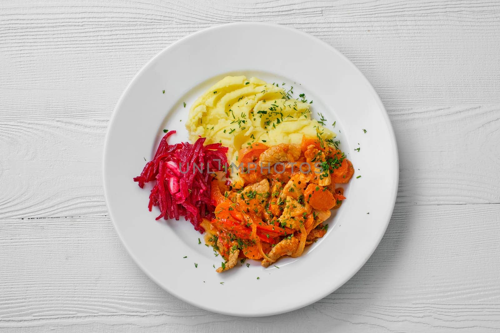 Top view of plate with beef goulash, mashed potato and beetroot salad