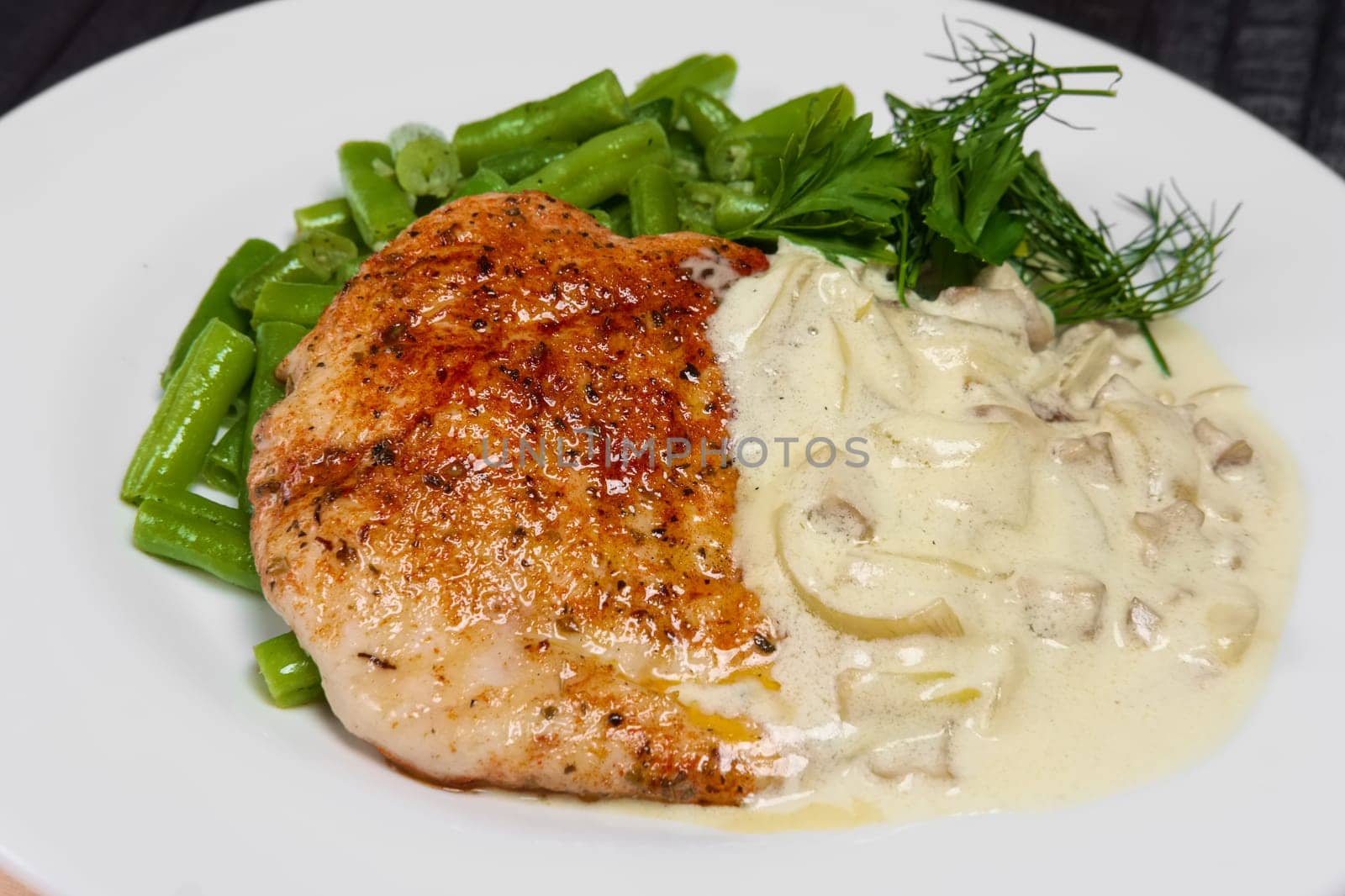 Closeup grilled steak and french green bean with creamy onion sauce.