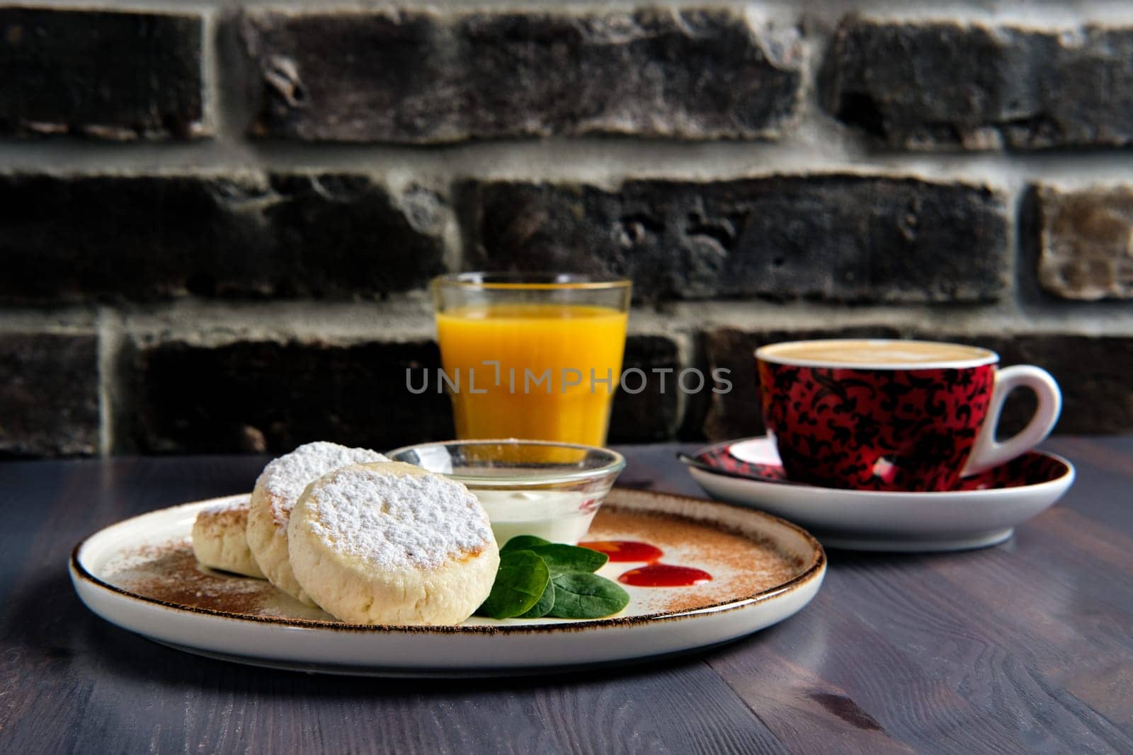 Traditional breakfast with cottage cheese pancake with sour cream, juice and latte