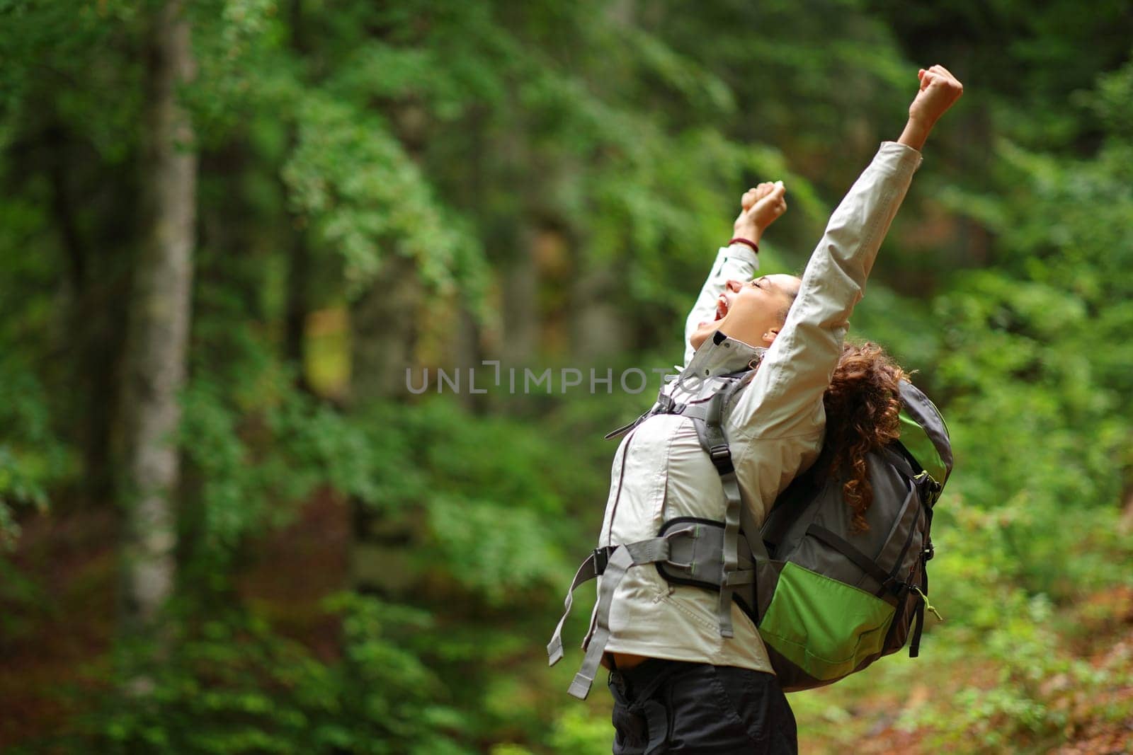 Hiker excited raising arms celebrating vacation in a forest