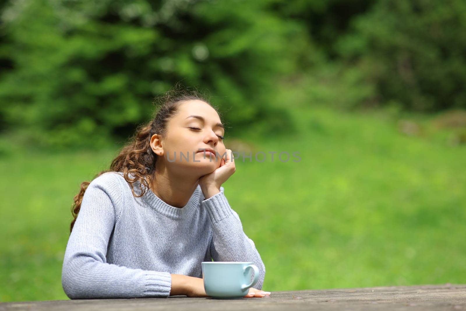 Woman sitting in a park drinking and relaxing