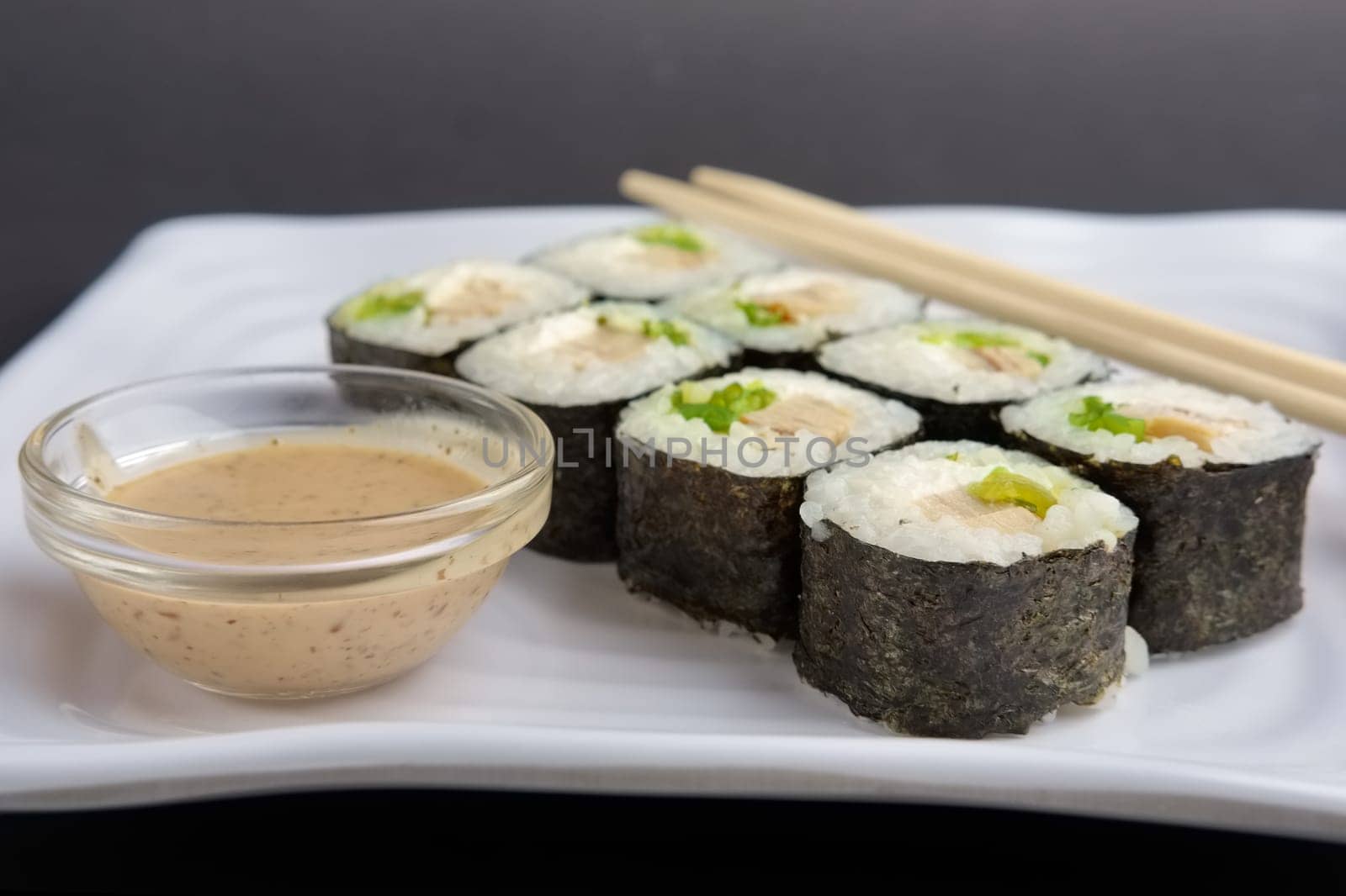 chicken roll with nori and nut sauce on white plate near hashi