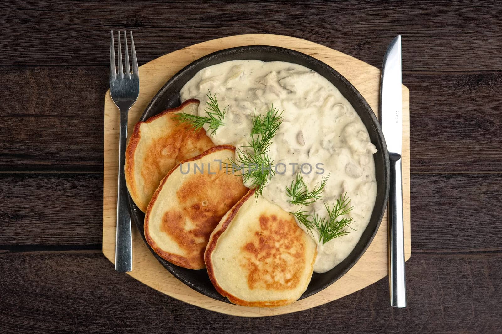 Flapjack with mushroom sauce on wooden plate. Top view.