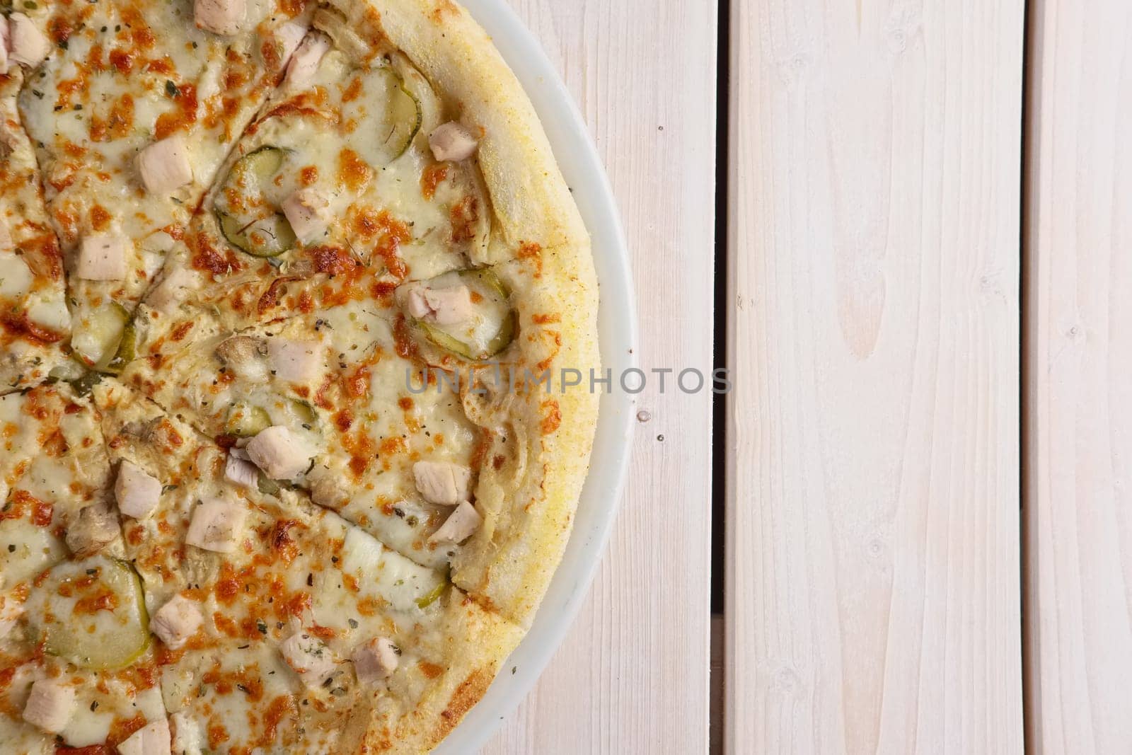 Fresh baked pizza with chicken fillet and pickled cucumber