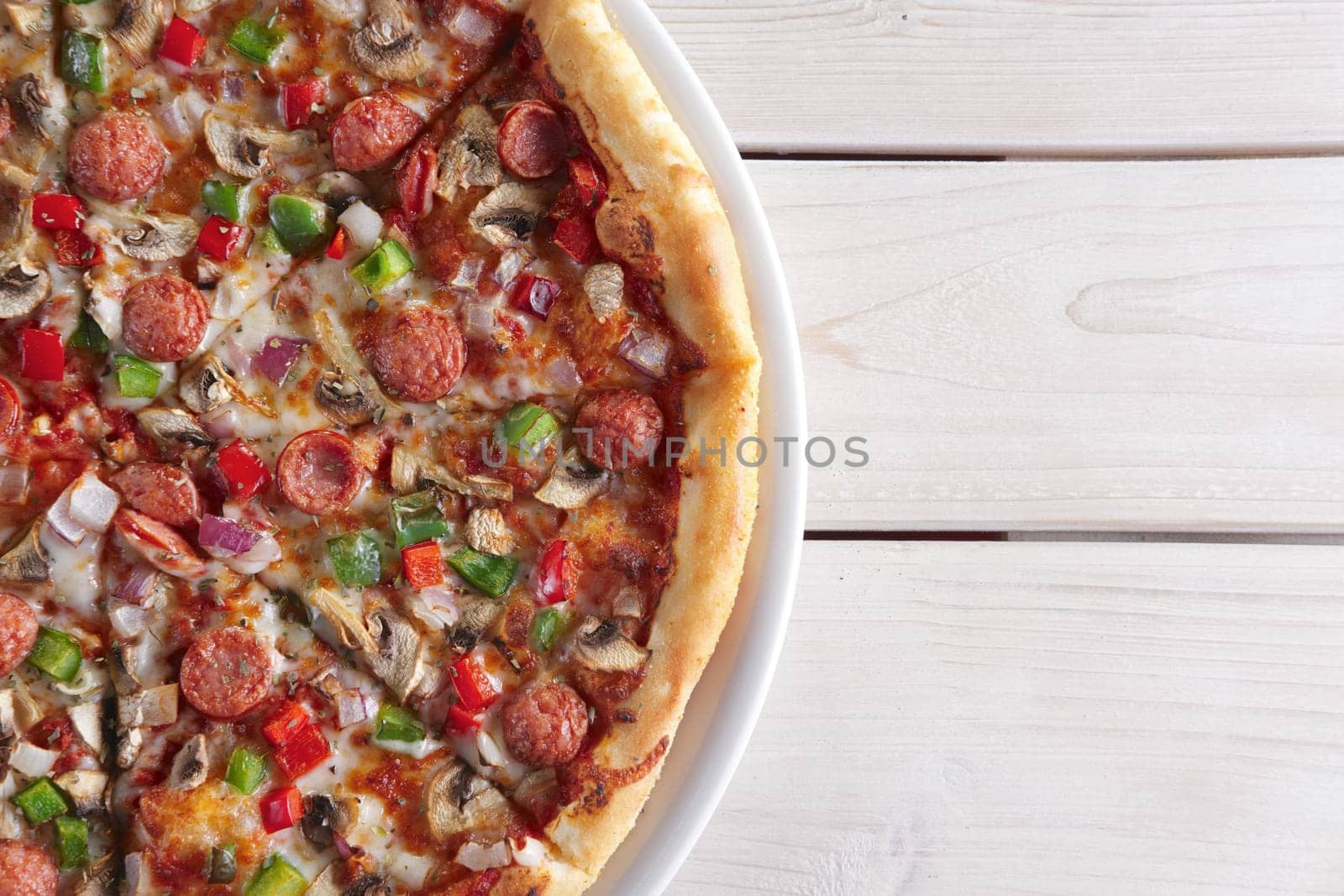 Pizza with sausage, ham, tomato, zucchini and paprika