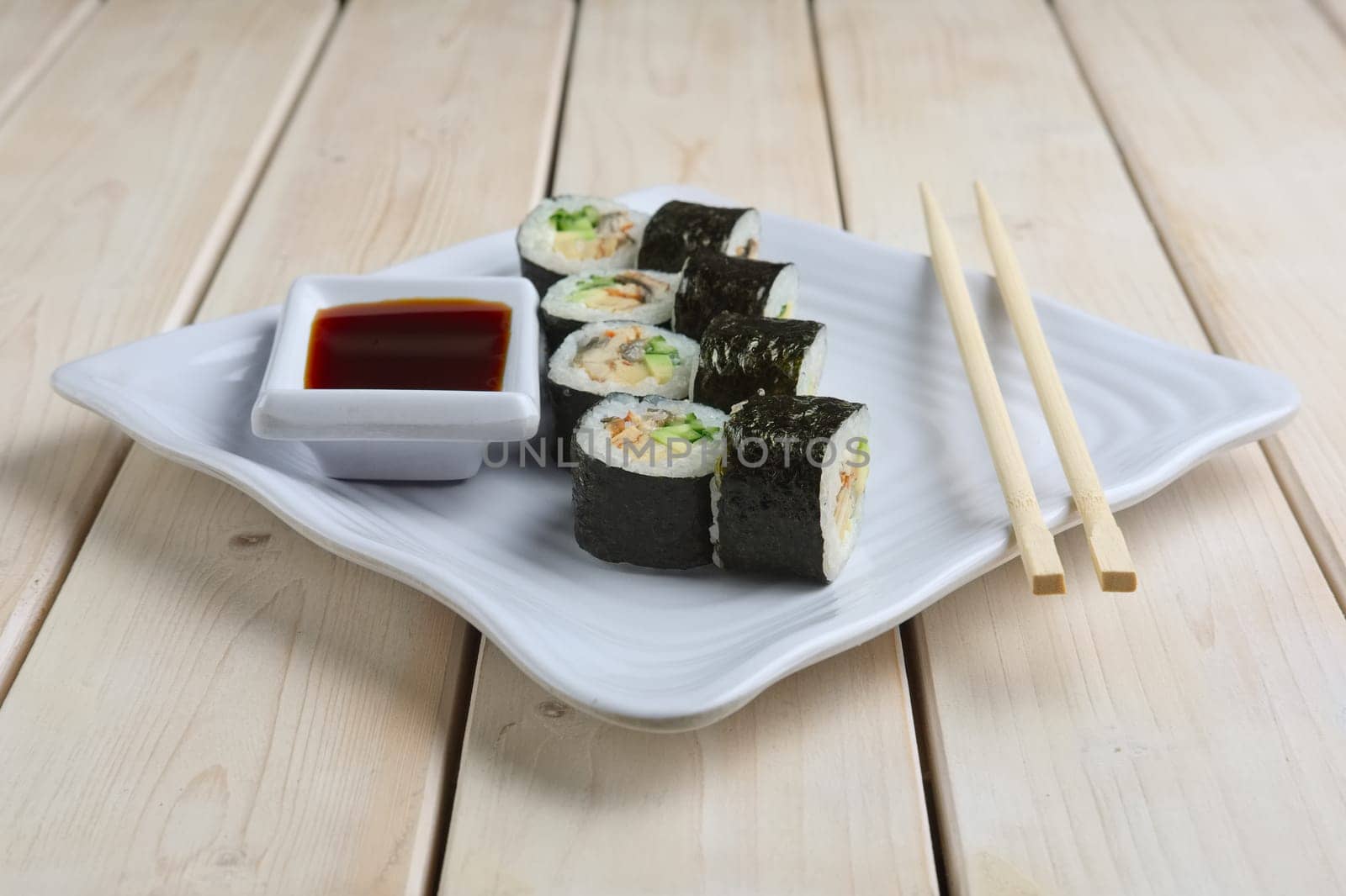 Set of rolls with salmon, avocado and cucumber on plate with soy sauce and hashi
