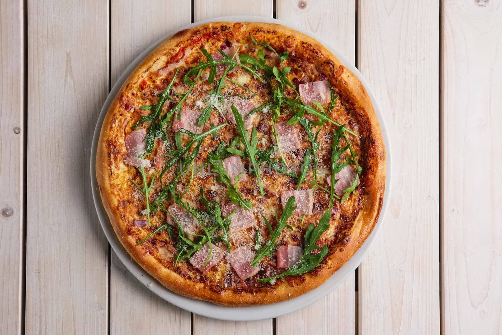 Pizza with bacon, bell pepper, onion and arugula