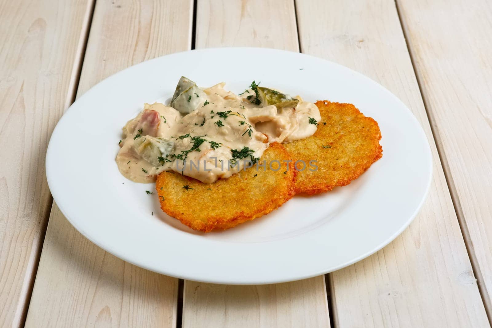 Potato pancakes with flour sauce and pickled cucumber and sausage