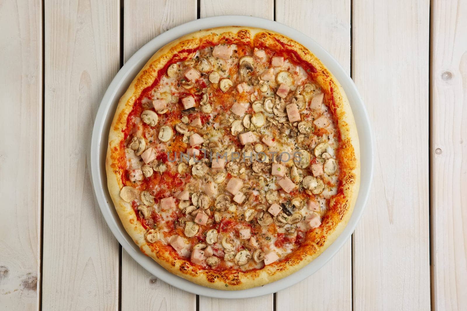 Top view of pizza with ham and champignon on wooden table
