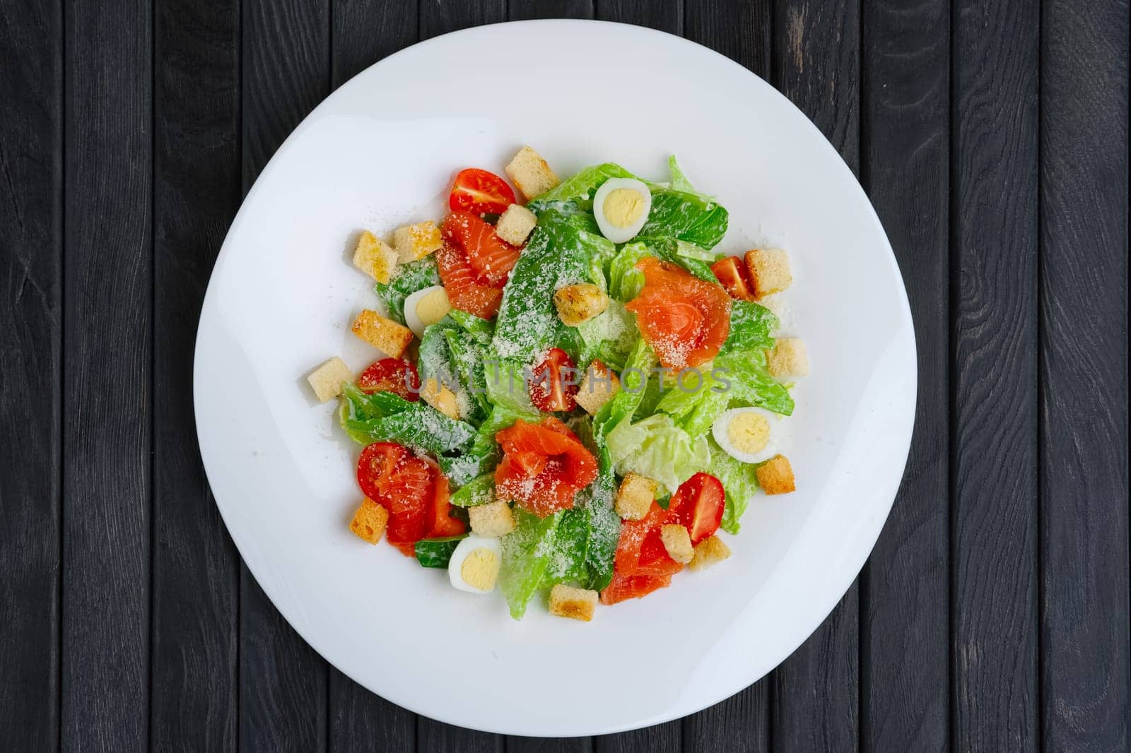 Top view of salad with quail egg, salmon fillet and vegetables with cheese