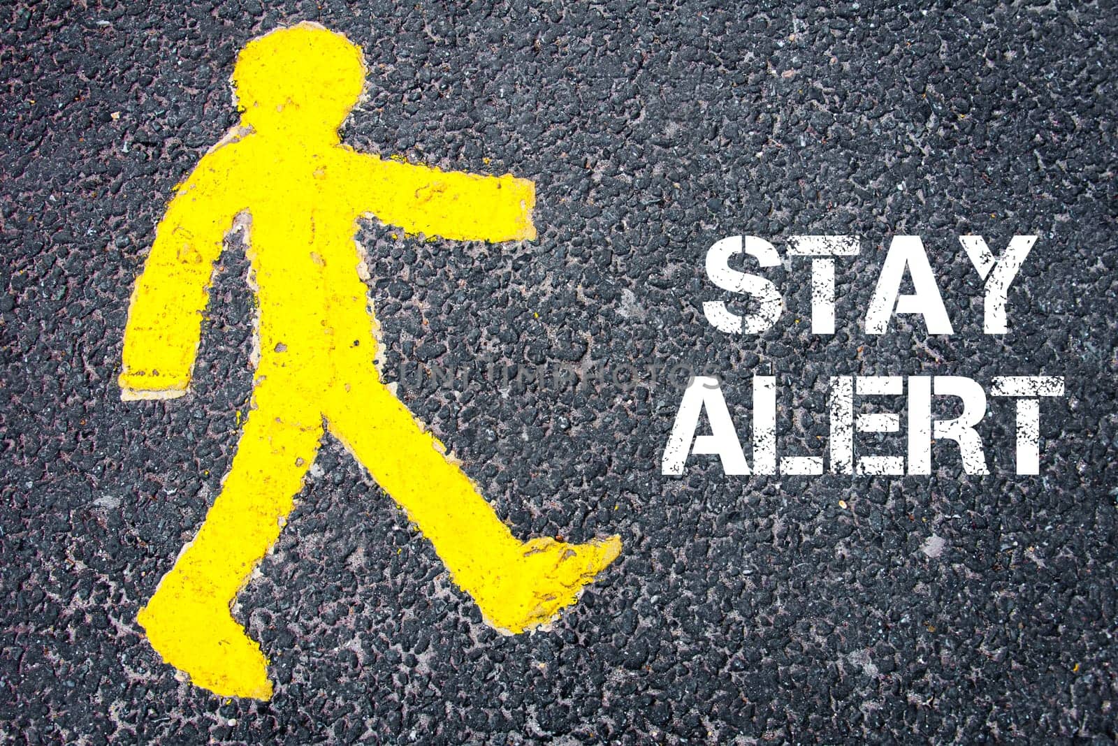 Yellow pedestrian figure on the road walking towards STAY ALERT. Conceptual image with Text message over asphalt background.