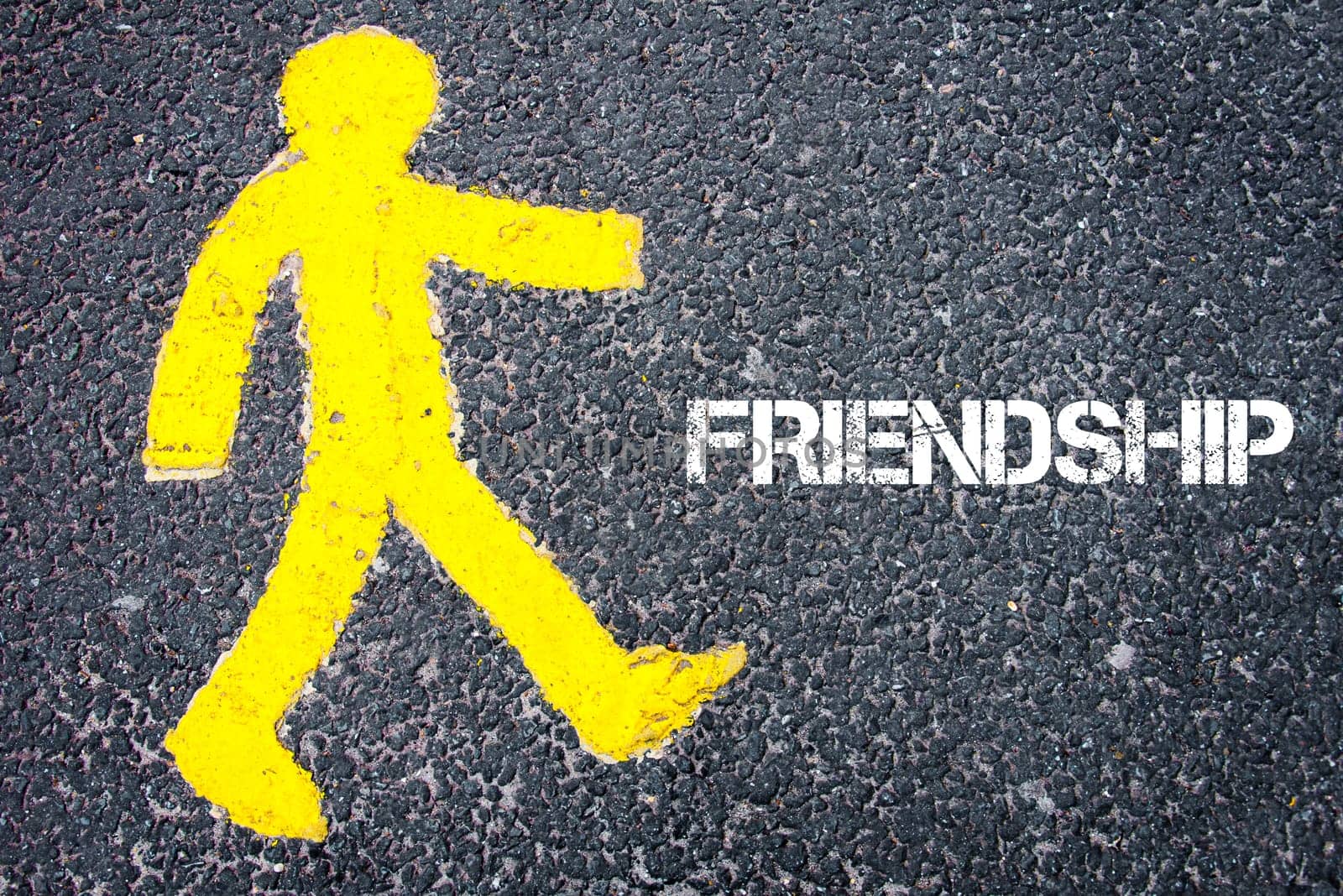 Yellow pedestrian figure on the road walking towards FRIENDSHIP. Conceptual image with Text message over asphalt background.