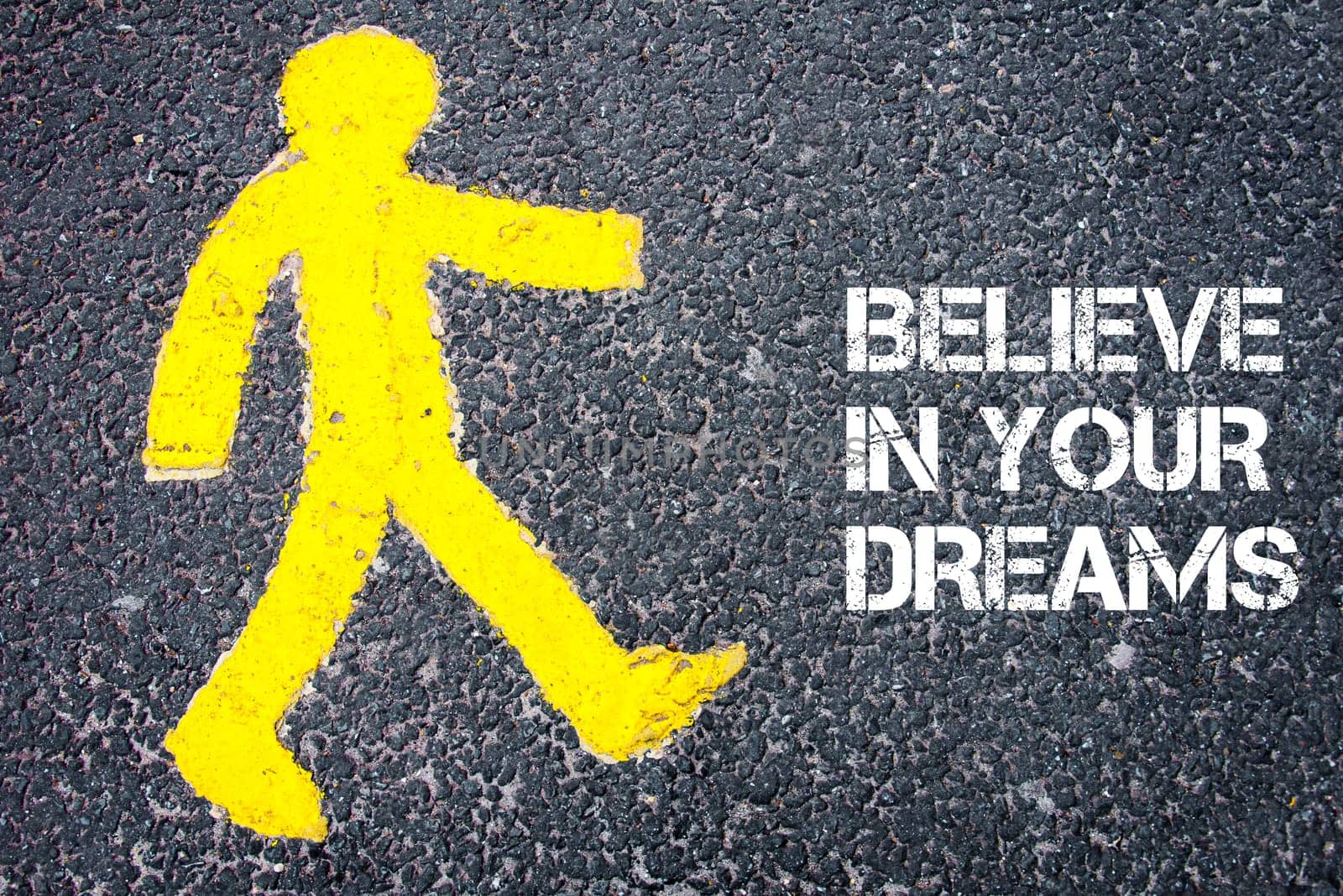 Yellow pedestrian figure on the road walking towards Believe in Your Dreams. Conceptual image with Text message over asphalt background.