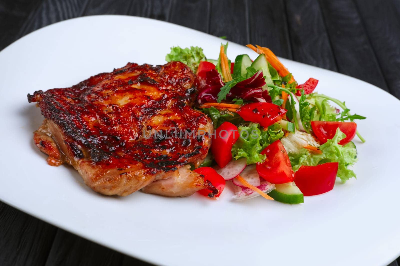 Juicy and crispy chopped pork fried on grill with fresh vegetables (red cabbage, tomato, cucumber, carrot and bell pepper)