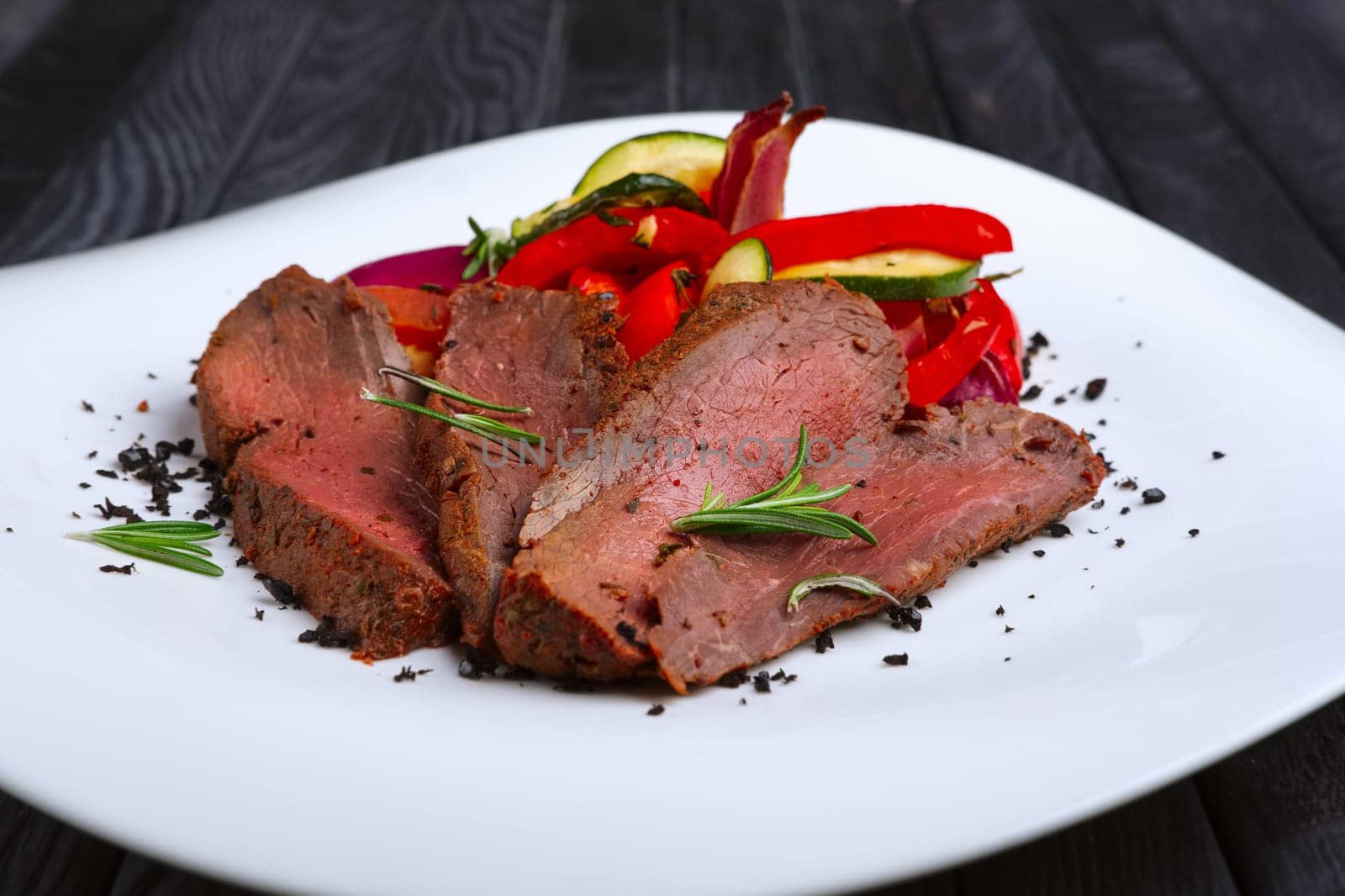Roasted beef cutted on slices with grilled bell pepper, zucchini, onion and fresh rosemary