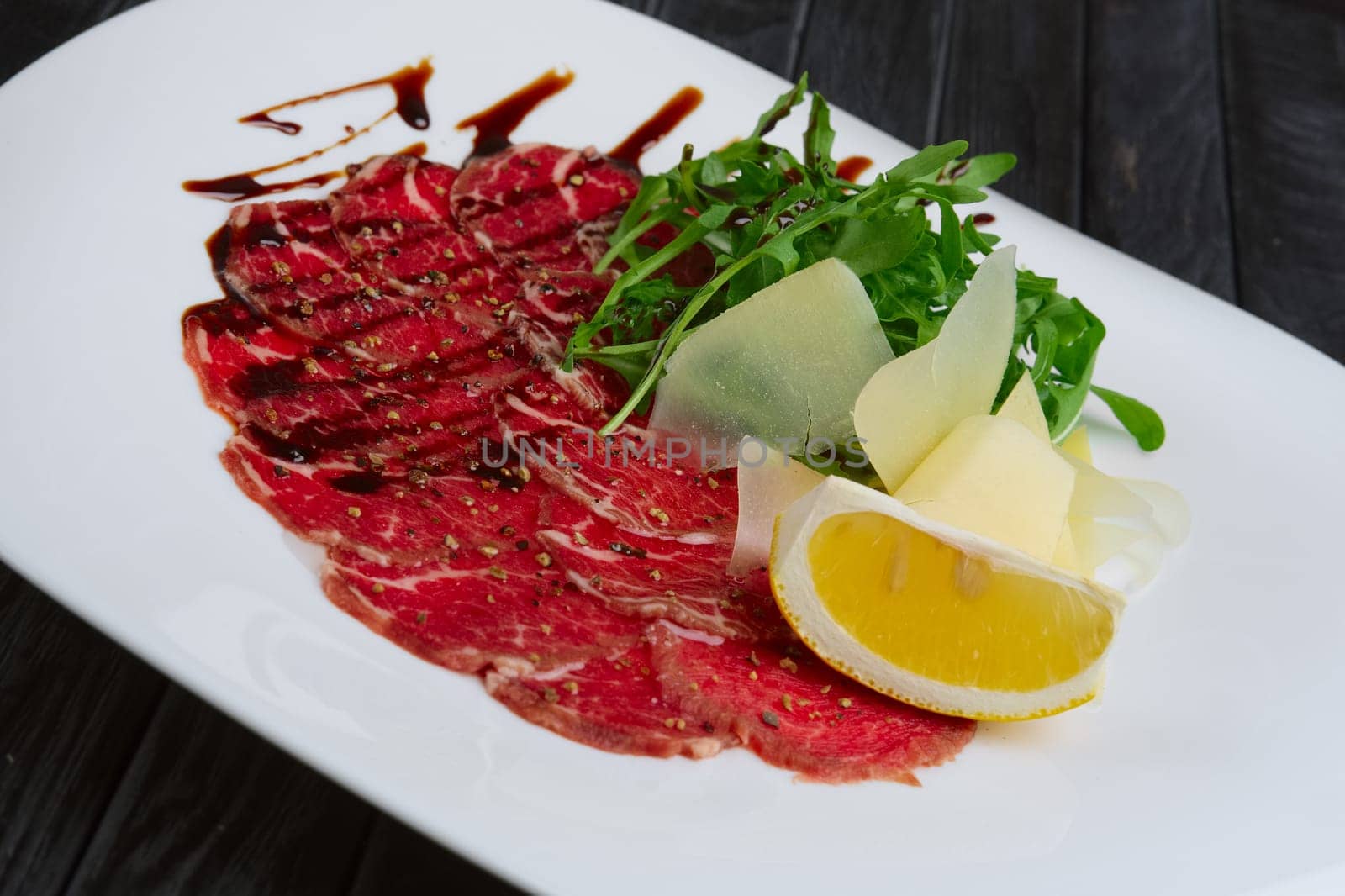 Beef carpaccio with cheese, white bread toasts and lemon