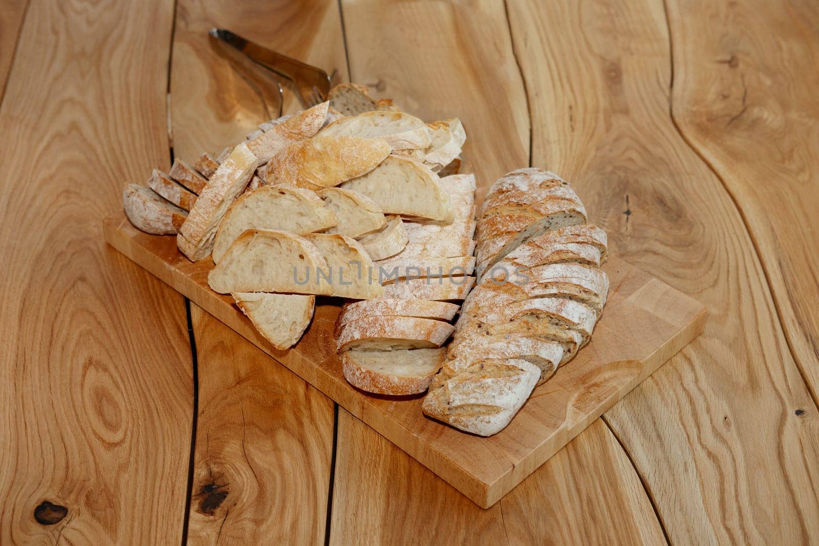 Cutted bread with seeds on board on rough wooden table